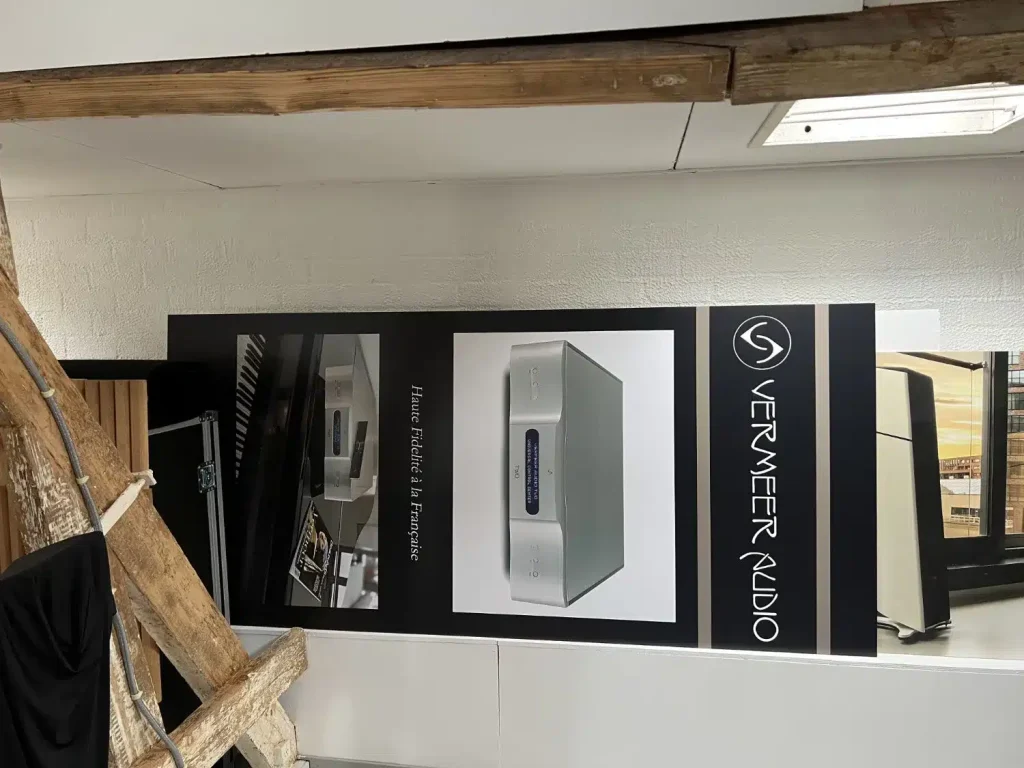 Un Vermeer Audio Three servait de DAC pour cette séance musicale, modèle de démonstration que j’avais d’ailleurs amené de Lyon à Paul et à Ivo pour qu’ils puissent le découvrir car ils n’avaient pas encore eu l’occasion de l’entendre. Ils étaient impatients car ils sont tous deux fans du modèle Two de VERMEER AUDIO, la preuve en image puisque les panneaux utilisés sur le salon de Munich 2019, lorsque les deux sociétés y partageaient un stand, sont stockés dans la grande salle
