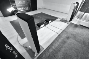 Paire d'enceintes Aequo Audio Stilla vues de haut avec des amplificateurs posés au sol et une moquette en premier plan