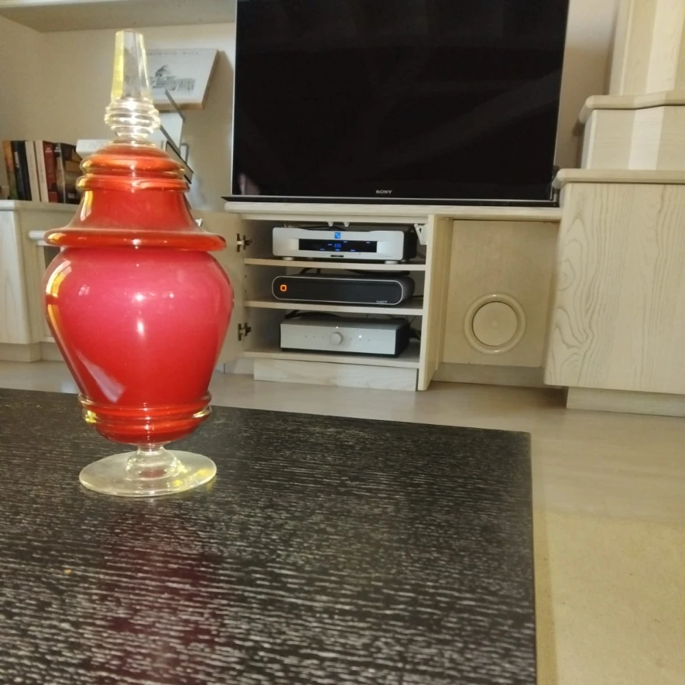 Derrière le premier plan qui comporte une table sombre et un objet rouge, un téléviseur et surtout un amplificateur intégré Mola-Mola Kula (et un XACT S1)